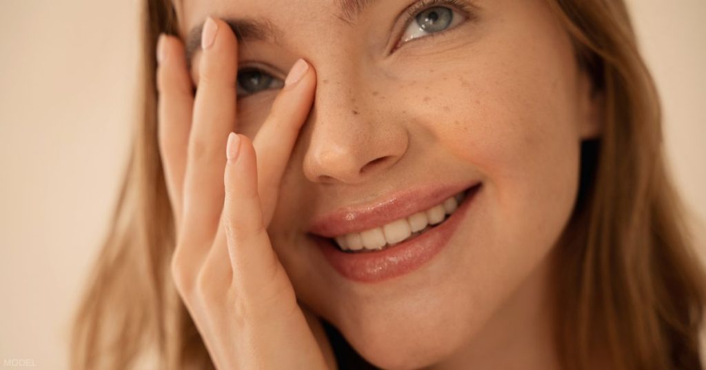 Woman with beautiful nose smiling and touching her face (model)