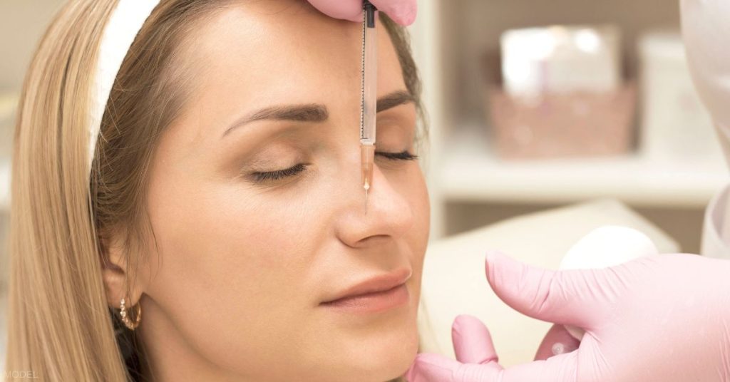 Women receiving dermal filler injections in her nose (model)